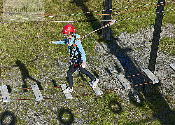 Teenager-Mädchen balanciert auf Planken auf einem Hochseilspielplatz in Island