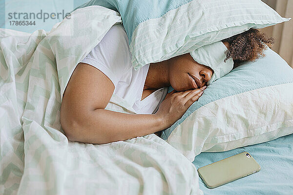 Lockige Frau schläft mit Schlafmaske im Gesicht.