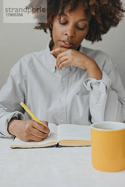Eine nachdenkliche Frau schreibt Gedanken in ein Tagebuch. Selektiver Fokus.