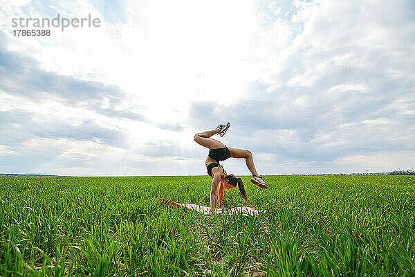 schönes Mädchenmodell auf grünem Gras macht Yoga