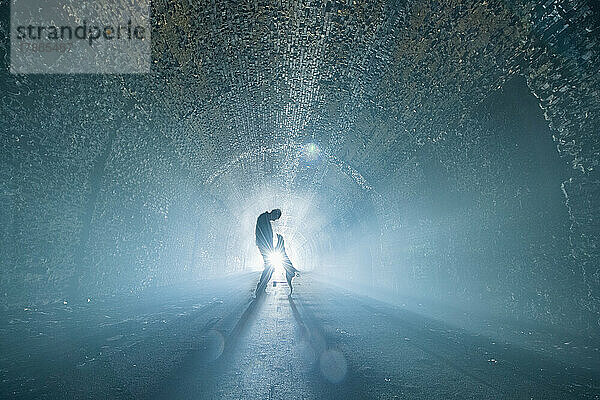 Mann und Hund laufen durch den beleuchteten Tunnel