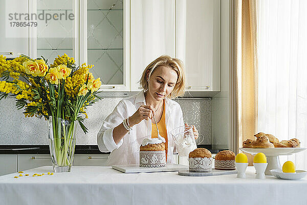 Eine Frau in der Küche dekoriert Ostergebäck.