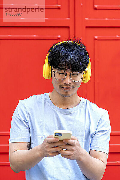Asiatischer Mann nutzt sein Smartphone  um Musik zu hören