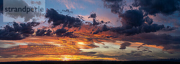 Ein Sonnenaufgang malt die Wolken in allen Farben des Regenbogens in Ebenen