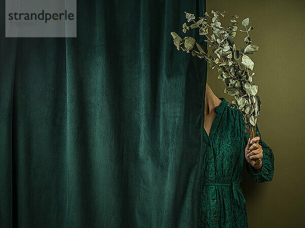 Mädchen versteckt sich hinter einem grünen Vorhang