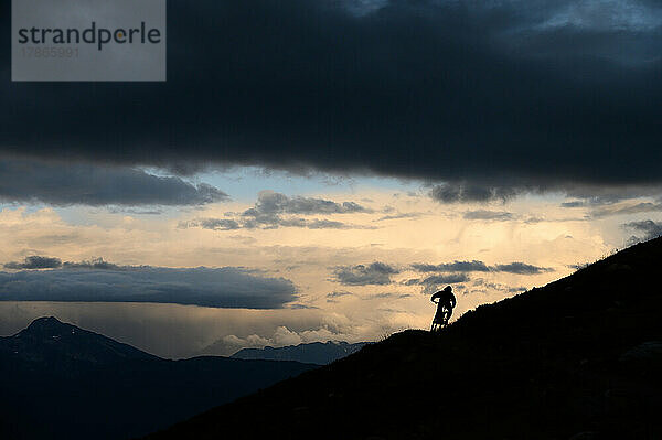 Mountainbiker kurven auf der Bergrückenlinie im Loomy Alpine Vista