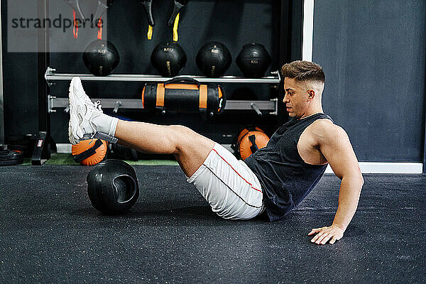 Mann macht Kräftigungsübungen mit Ball auf der Matte im Fitnessstudio