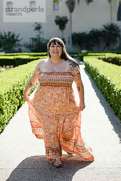 Plus-Size-Model trägt langes orangefarbenes Kleid in San Diego
