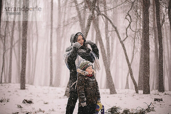 Mutter und Sohn stehen bei Schneefall im Winter im Park
