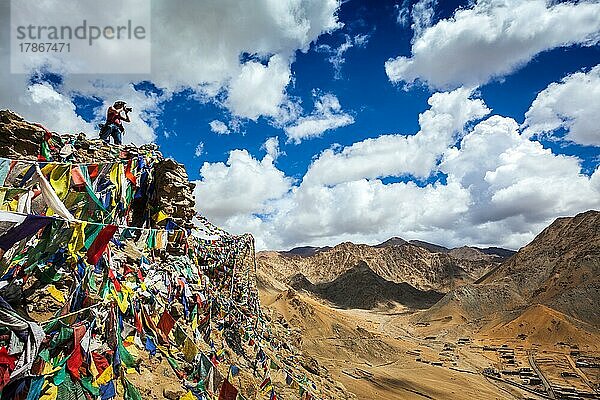 Reisefotograf fotografiert in den Bergen des Himalaya auf einer Klippe mit buddhistischen Gebetsfahnen. Leh  Ladakh  Jammu und Kaschmir  Indien  Asien