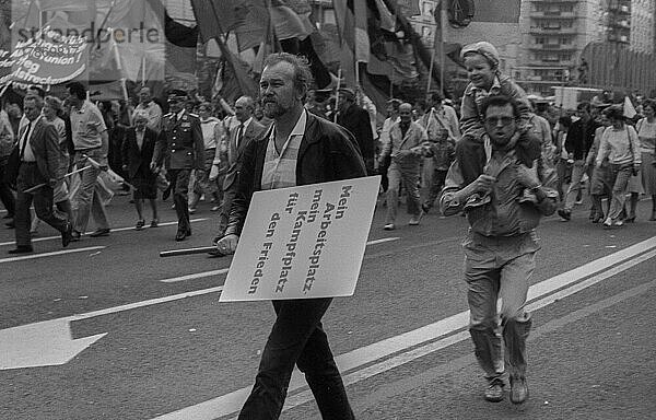 DDR  Berlin  01. 05. 1987  1. Mai Kundgebung 1987 auf der Karl-Marx-Allee  Regenschauer  Plakat: Mein Arbeitsplatz  mein Kampfplatz für den Frieden