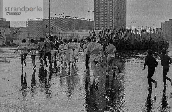DDR  Berlin  01. 05. 1987  1. Mai Kundgebung 1987 auf der Karl-Marx-Allee  Regenschauer  Teilnehmer rennen Richtung Alex (Alexanderplatz)