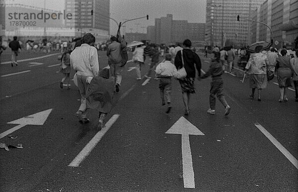 DDR  Berlin  01. 05. 1987  1. Mai Kundgebung 1987 auf der Karl-Marx-Allee  Regenschauer  Teilnehmer rennen Richtung Alex (Alexanderplatz)
