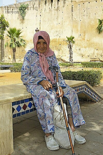 Alte Frau im traditionellen Djellaba oder Kaüzenmantel  hinten die Stadtmauer  Meknès  Marokko  Afrika