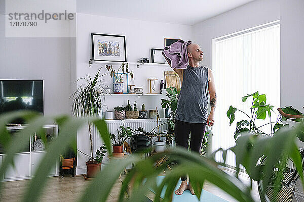 Mann wischt sich zu Hause im Wohnzimmer den Kopf mit einem Handtuch ab