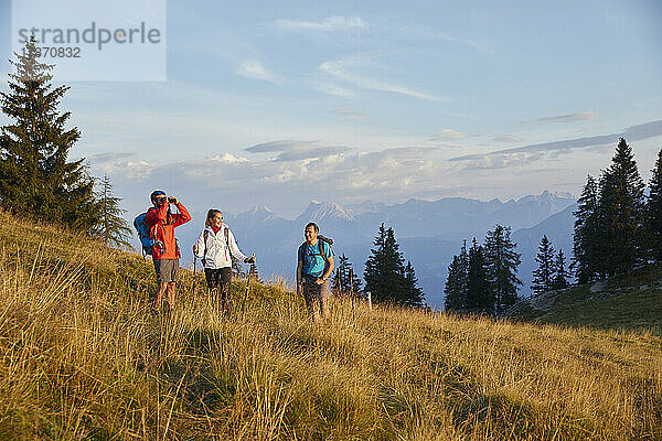 Mann schaut durch ein Fernglas und steht mit Freunden am Berg  Mutters  Tirol  Österreich
