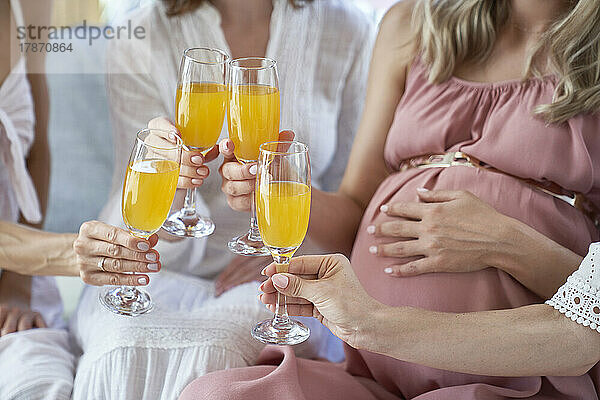 Hände von Frauen  die bei der Babyparty mit Cocktailgläsern anstoßen