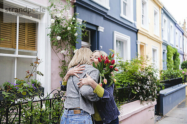 Mutter und Tochter umarmen sich in der Stadt mit Tulpenblumen