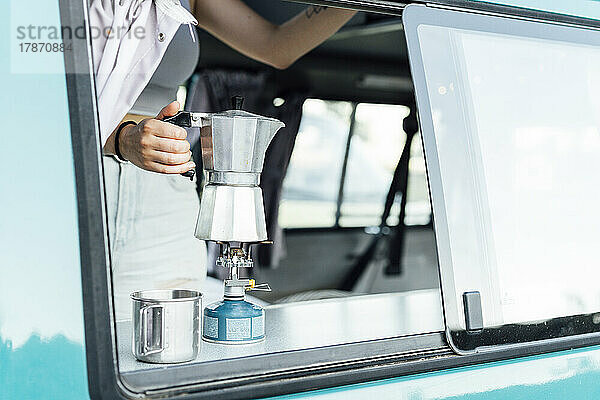 Frau bereitet Kaffee auf Herd mit Kaffeemaschine im Lieferwagen zu
