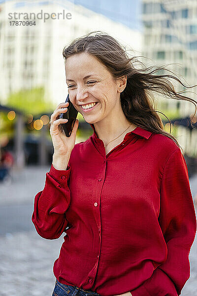 Glückliche Frau  die am Smartphone spricht