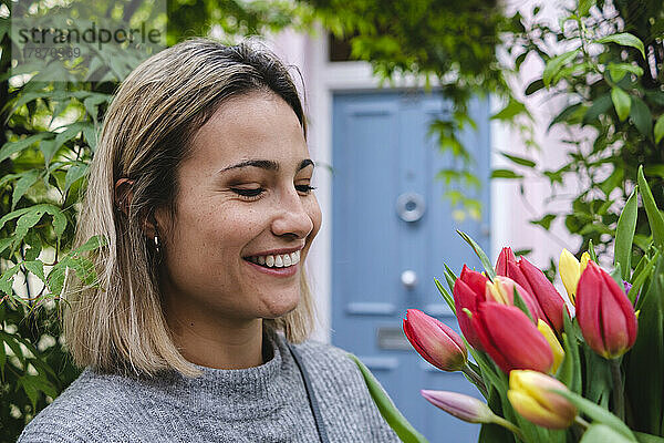 Lächelnde Frau  die Tulpenblumen betrachtet