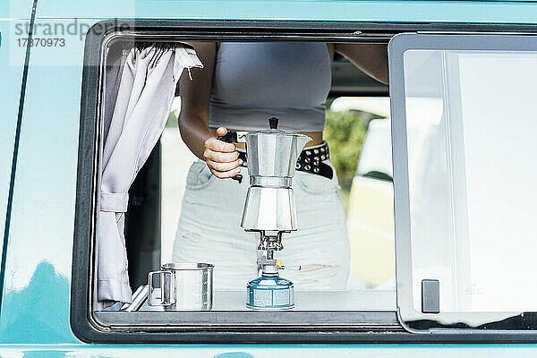Junge Frau bereitet Kaffee im Lieferwagen zu