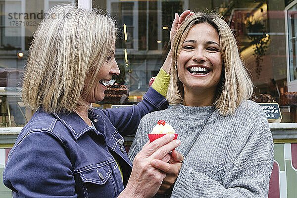 Glückliche Mutter und Tochter mit Cupcake vor der Bäckerei