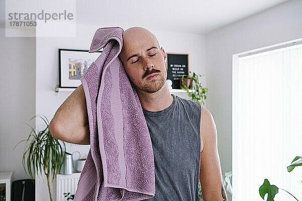 Mann wischt sich zu Hause den Kopf mit einem Handtuch ab