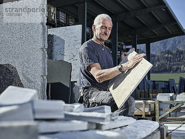 Reifer Steinmetz untersucht Steinplatte in der Werkstatt