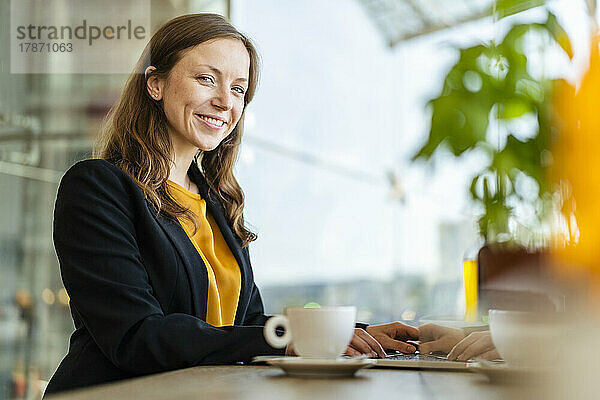 Lächelnde Geschäftsfrau mit Laptop im Café