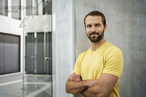 Happy young man with beard standing in front of wall