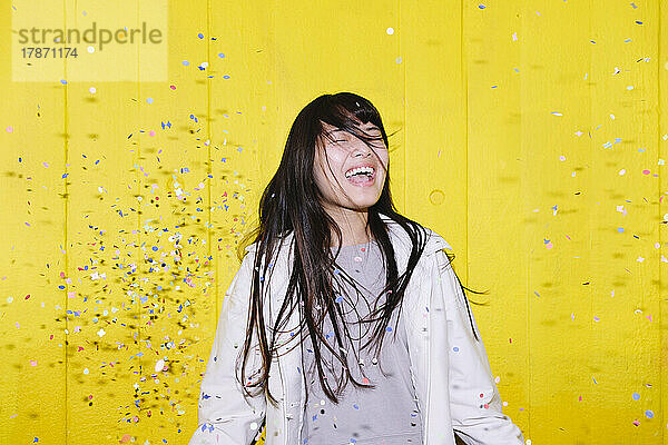 Cheerful woman celebrating with confetti in air