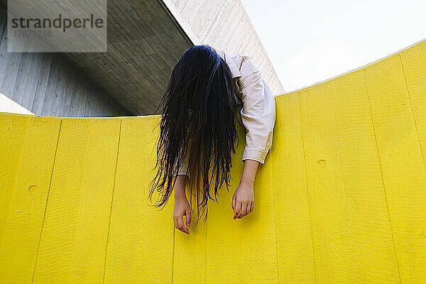 Bewusstlose junge Frau lehnt an gelber Wand