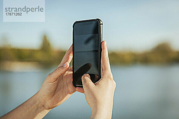 Die Hand einer Frau fotografiert mit dem Mobiltelefon