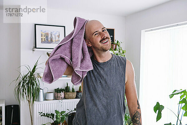 Glücklicher Mann wischt sich zu Hause den Kopf mit einem Handtuch ab