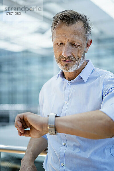 Reifer Geschäftsmann überprüft die Zeit auf der Armbanduhr