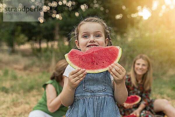 Cute girl holding watermelon standing at park