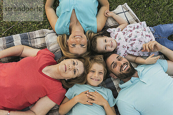 Glückliche Familie liegt auf einer Decke im Park
