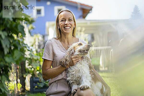 Porträt einer lächelnden Frau mit Hund im Garten