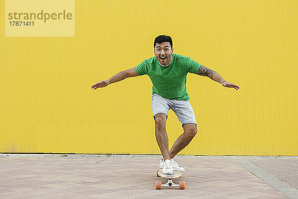 Glücklicher junger Mann  der auf Skateboard balanciert