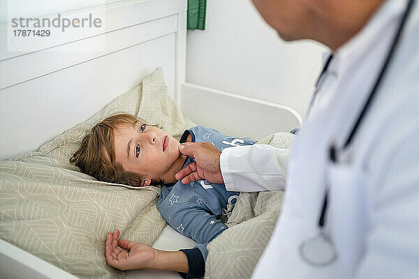 Arzt untersucht Jungen zu Hause im Bett