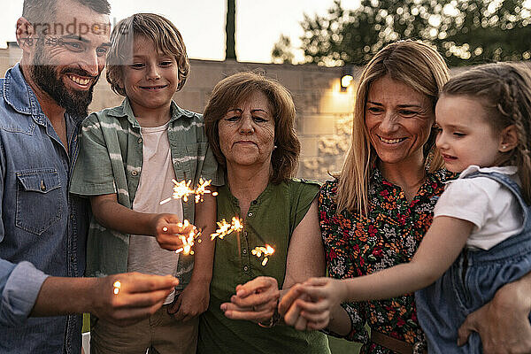 Lächelnde Familie brennt gemeinsam Wunderkerzen