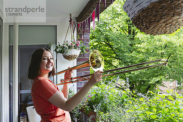 Lächelndes Mädchen mit Posaune  das auf dem Balkon steht