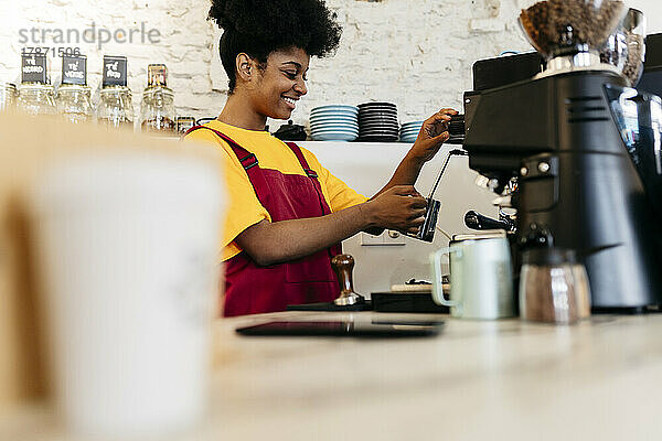 Lächelnde Frau kocht Kaffee im Café