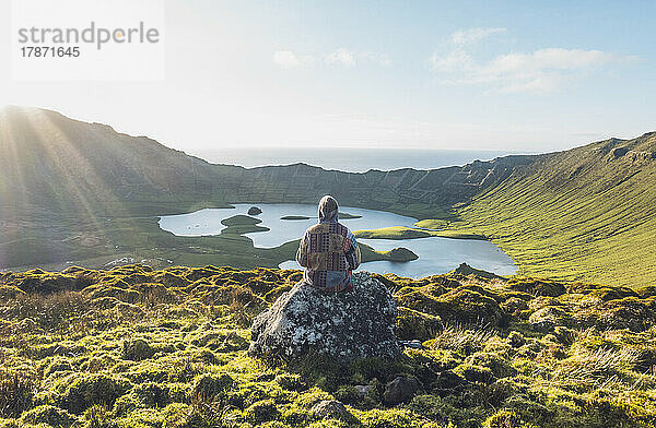 Young woman sitting on rock at Corvo Island  Azores  Portugal