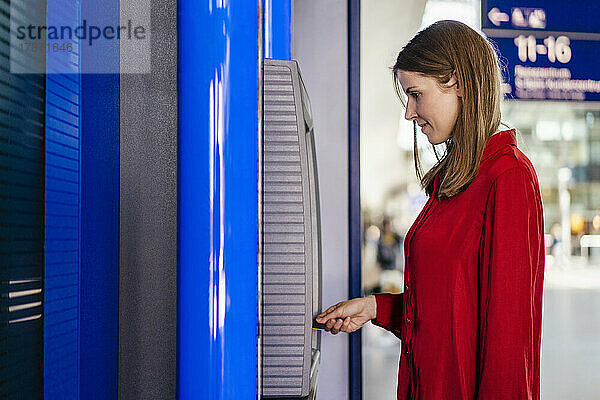 Geschäftsfrau steckt Karte am Geldautomaten ein