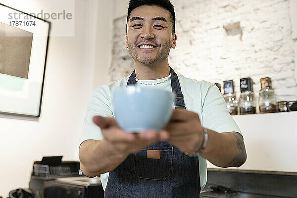 Happy man offering coffee cup