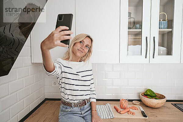 Lächelnde junge Frau  die zu Hause ein Selfie mit dem Smartphone macht