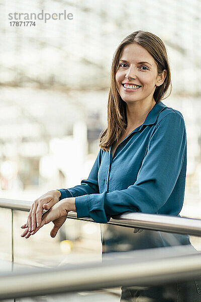 Smiling businesswoman by railing in office