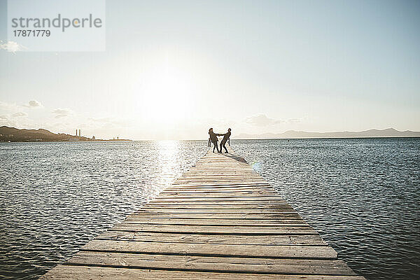 Happy couple enjoying on jetty over sea